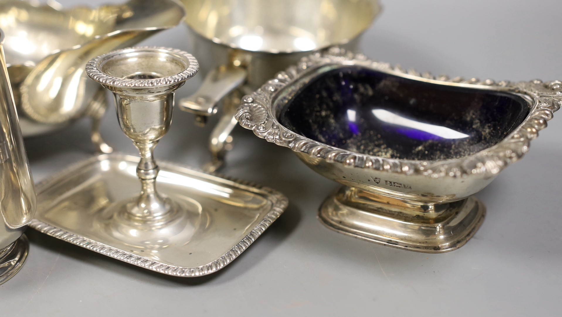 A pair of late Victorian silver sauceboats, Frederick Augustus Burridge, London, 1899, a George V silver mounted taperstick, a modern silver three piece condiment set, a silver chamberstick, silver mug, two silver small